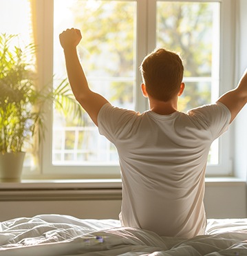 Man waking up refreshed after night of good sleep